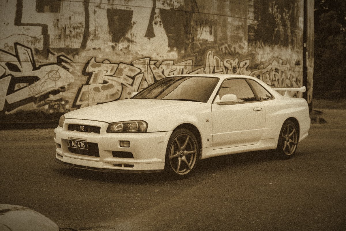 Nissan Skyline GT-R R34 blanche devant un mur couvert de graffitis