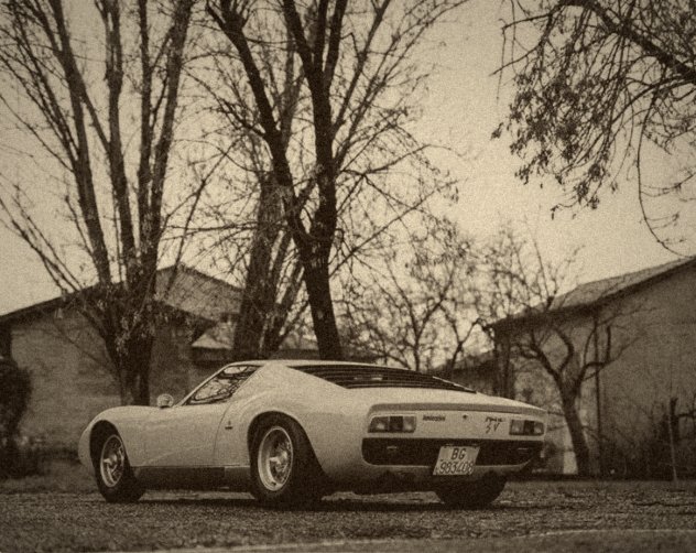 Lamborghini Miura SV jaune, vue de trois-quarts arrière, dans une allée bordée d'arbres